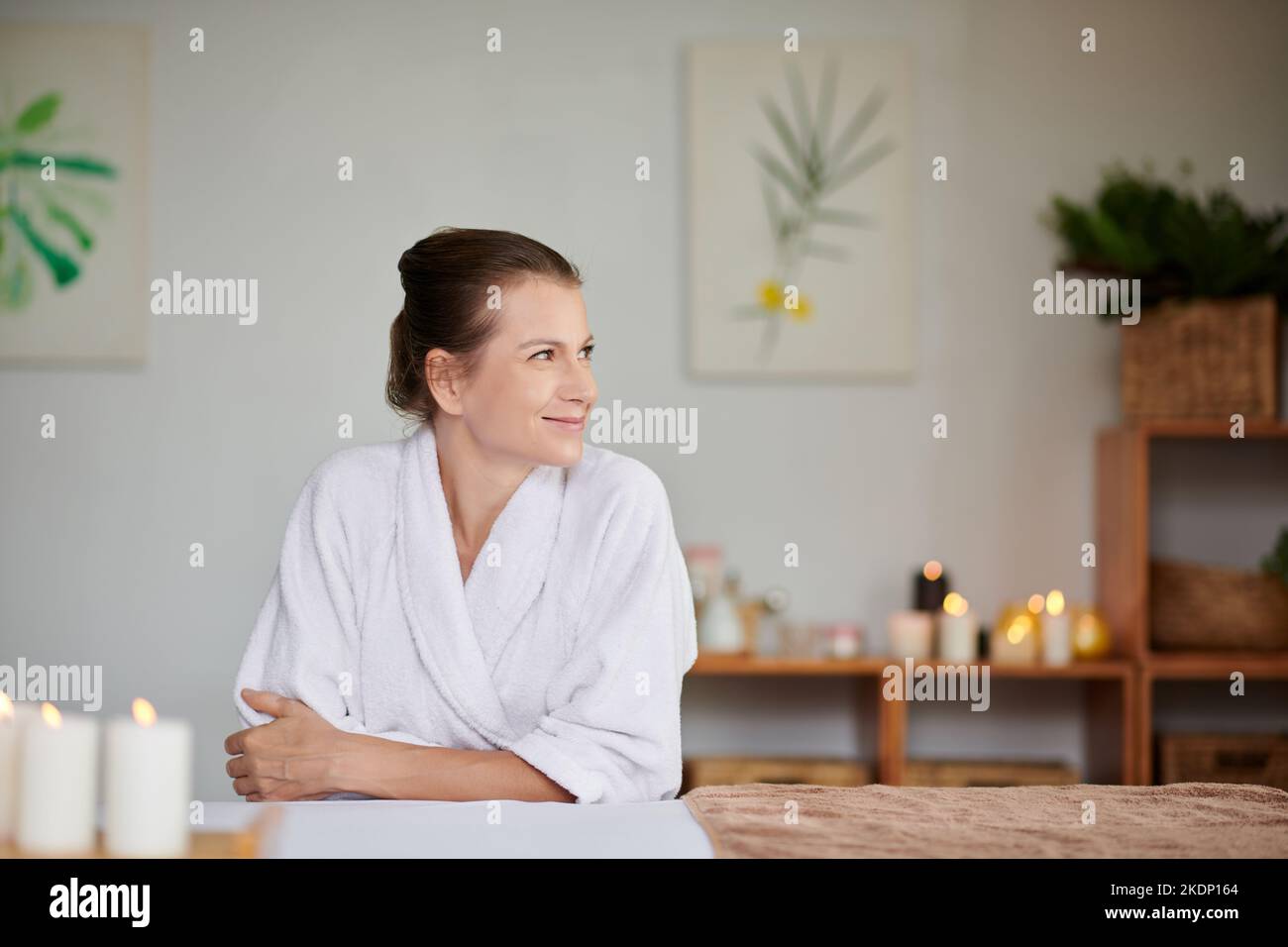 Lächelnde Frau im weichen Badetuch genießt das Wochenende im Spa Salon Stockfoto
