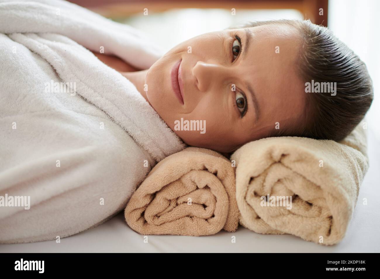 Porträt einer lächelnden, reifen Frau, die sich nach einer verjüngenden Behandlung im Spa-Salon auf dem Bett ausruhte Stockfoto