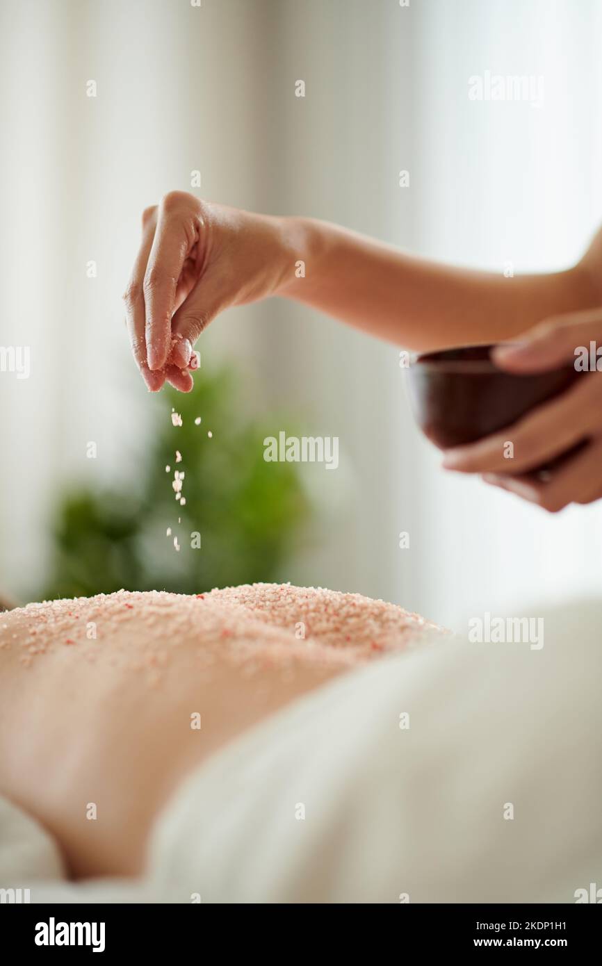 Nahaufnahme der Frau, die auf dem Rücken der Kundin des Spa-Salons ein infundierten Salzpeeling einkneift Stockfoto