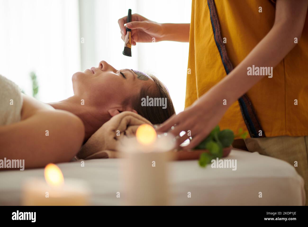 Nahaufnahme Bild der Kosmetikerin Anwendung entgiftende und aufhellende Tonmaske auf Gesicht der reifen Frau Stockfoto