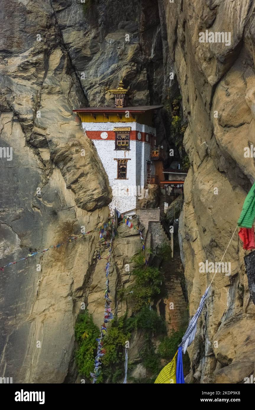 Atemberaubende Dependance des buddhistischen Klosters Paro Taktsang alias Tiger's Nest, das zwischen Felsklippen im Westen Bhutans mit traditionellen Gebetsfahnen erbaut wurde Stockfoto