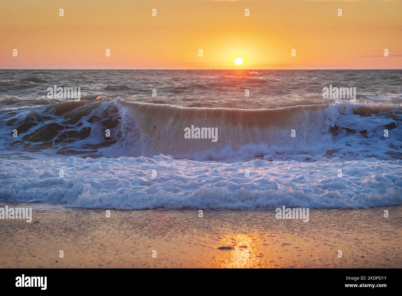 Wellen Sie während des Sonnenuntergangs an der Küste. Stockfoto