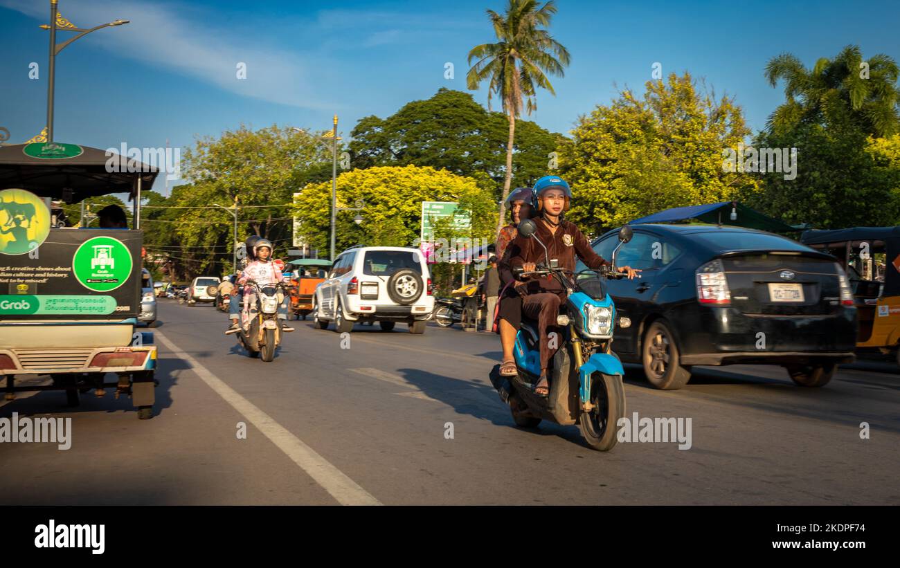 Eine junge Frau fährt im Zentrum von Siem Reap in Kambodscha entlang des Flusses Siem Reap ein Motorrad. Stockfoto