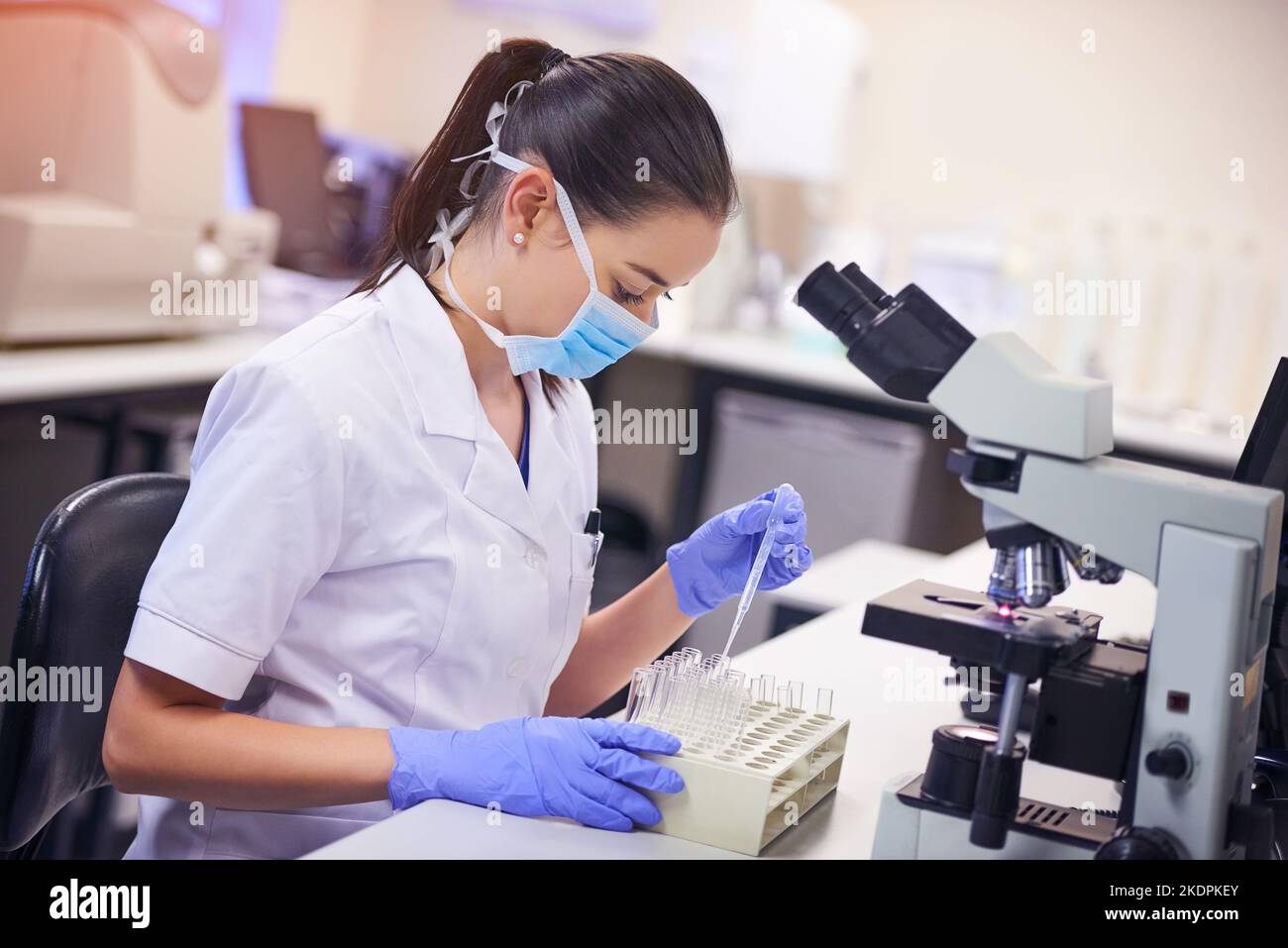Shes macht Wellen mit ihrer Forschung in der medizinischen Welt. Eine junge Wissenschaftlerin, die Flüssigkeit von einer Pipette in ein Reagenzglas in einem Labor überträgt. Stockfoto