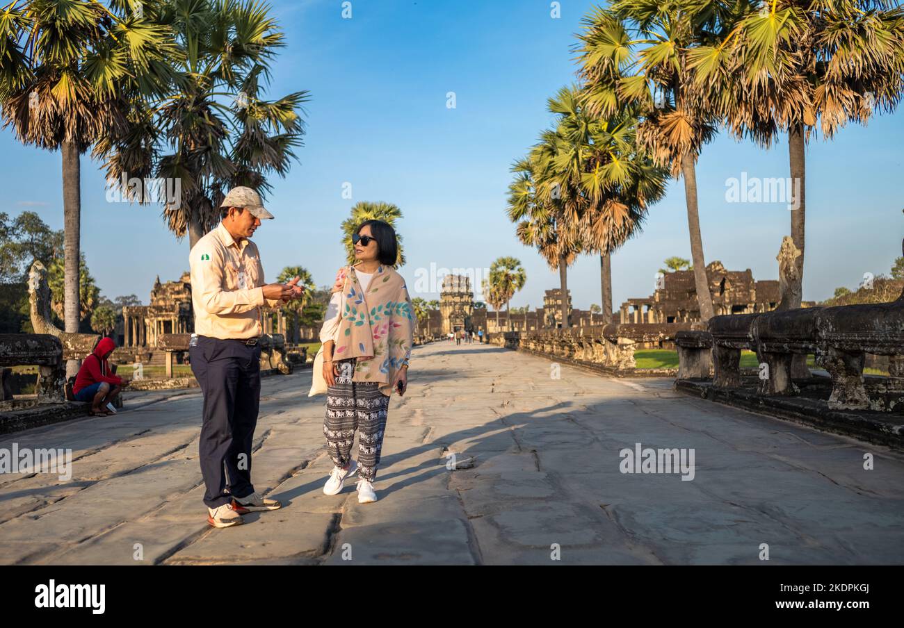 Ein offizieller Reiseleiter im Angkor Wat in Kambodscha spricht mit einer vietnamesischen Besucherin am Haupteingang des Tempels. Stockfoto