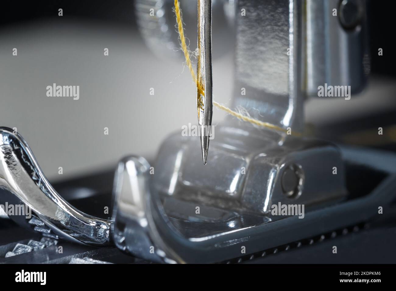 Gelbe Fadennadel und Nähmaschinenfuß. Makrofotografie. Stockfoto