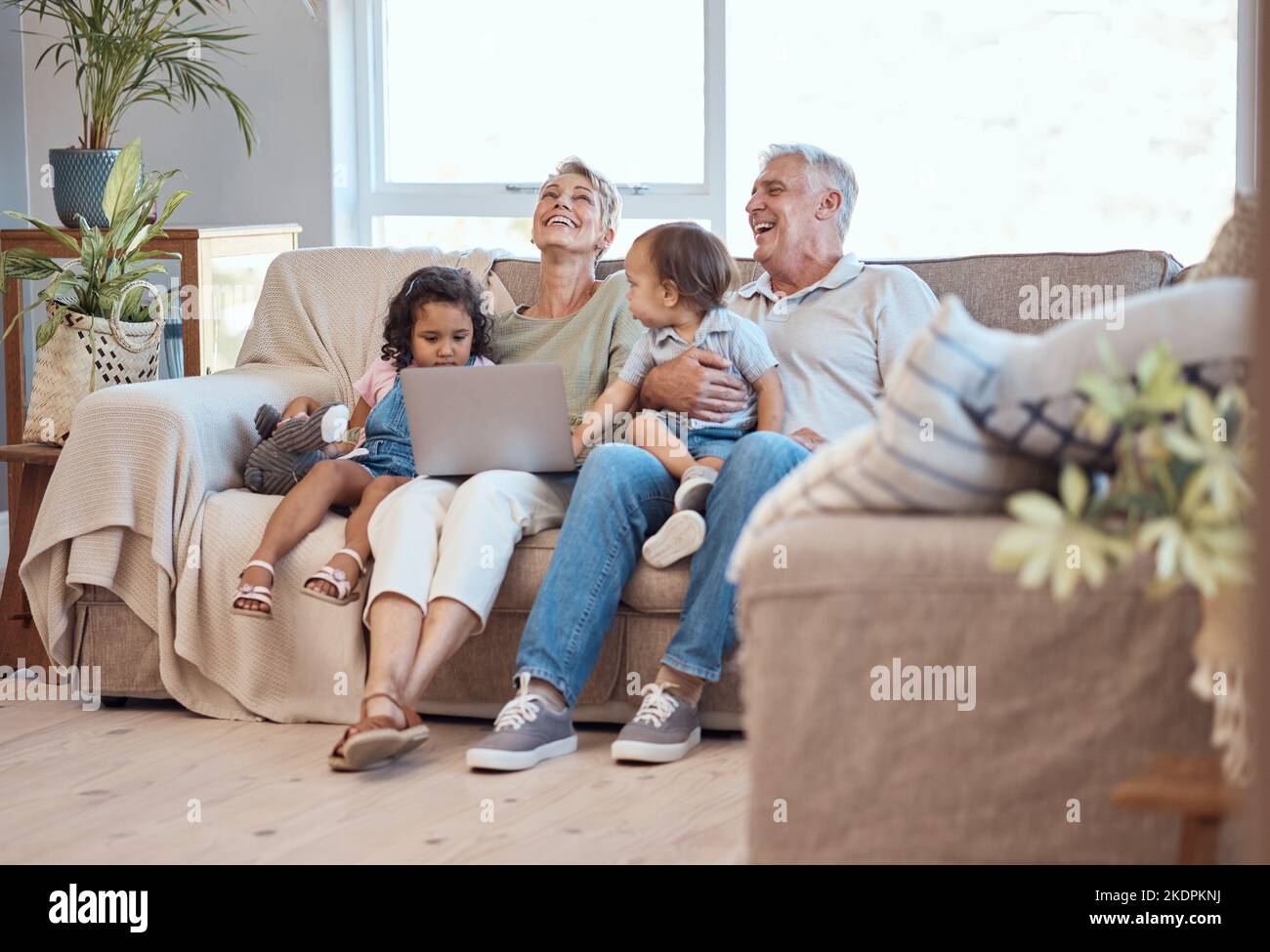 Glücklich, Familie und Laptop auf dem Sofa mit Kindern und Großeltern auf dem Sofa zu Hause. Ältere Männer und Frauen entspannen sich online mit ihren Adoptivkindern Stockfoto