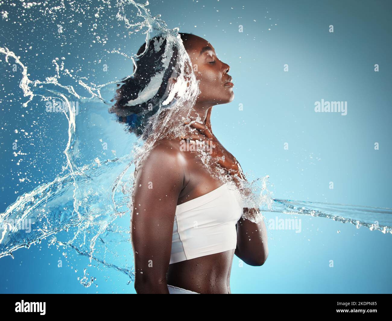 Wasser, Spritzer und eine Frau, die ihren Körper auf einem blauen Studiohintergrund wäscht, um die Hygiene zu reinigen. Reinigung, waschen und afroamerikanische Frau mit Pflege Stockfoto