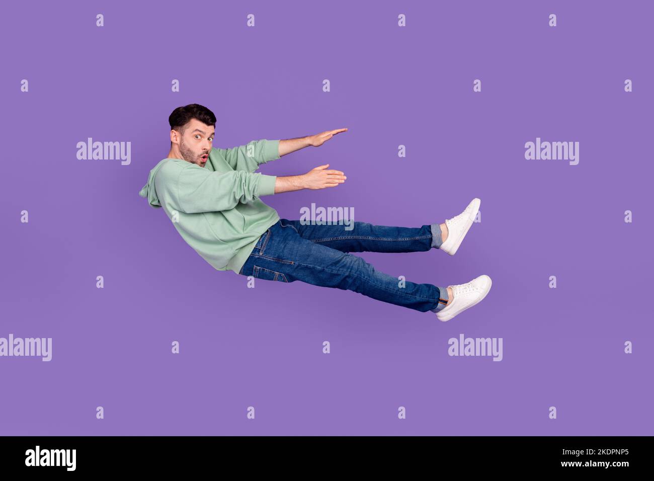 In voller Länge Foto von schönen jungen Kerl wegfliegen rückwärts verwirrt Mühe tragen trendige graue Outfit isoliert auf violetten Hintergrund Stockfoto