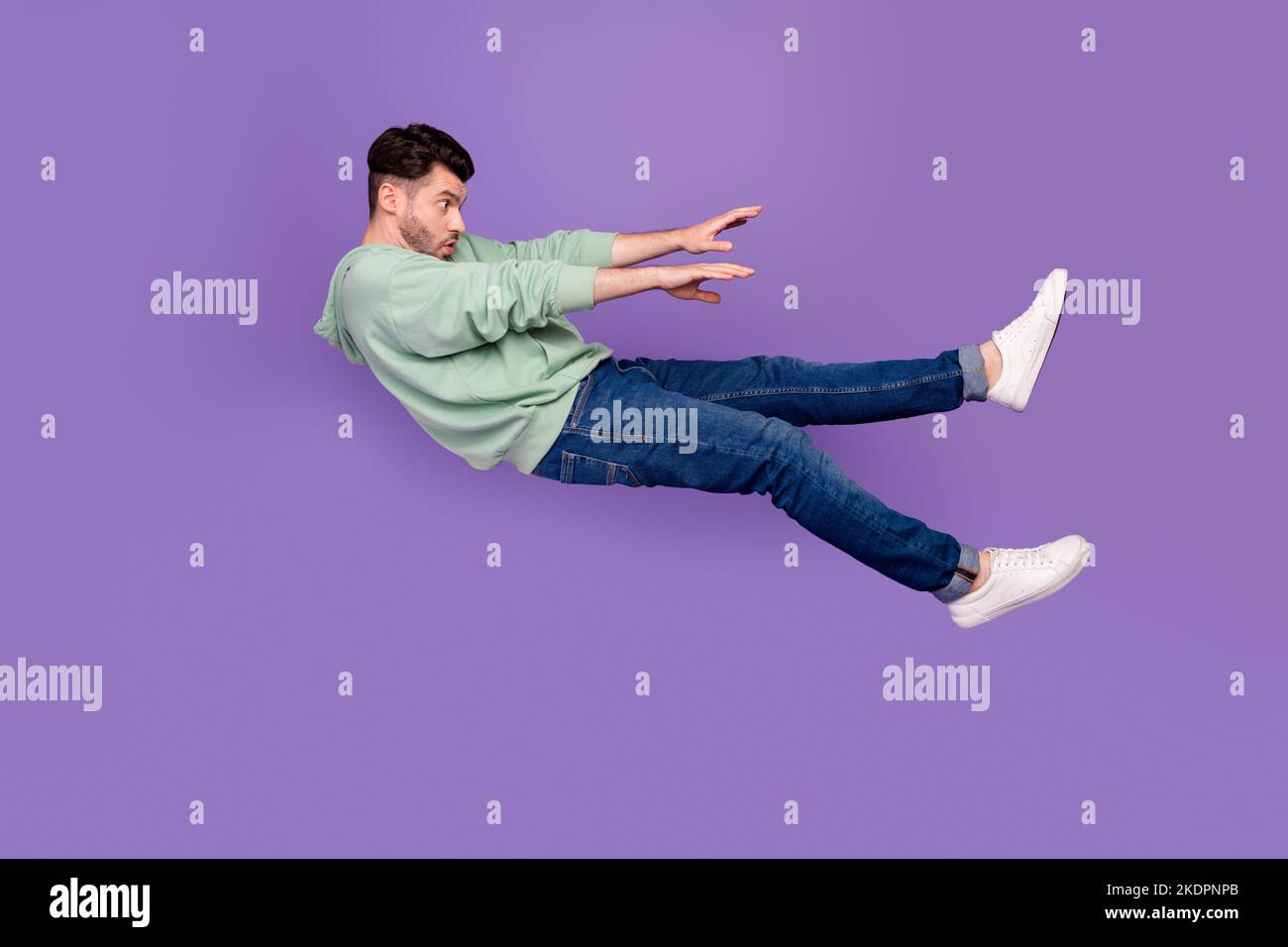 Foto in voller Größe von schönen jungen Mann wegfliegen starken Wind Schlag drücken gekleidet stilvolle khaki Kleidung auf lila Hintergrund isoliert Stockfoto