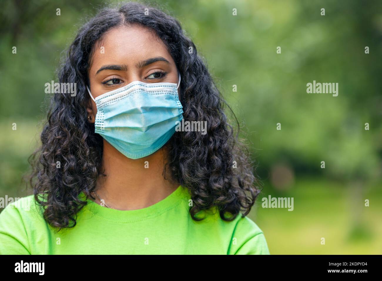 Afroamerikanische Biracial Mädchen Teenager Teenager gemischte Rasse weibliche junge Frau außerhalb trägt chirurgische Gesichtsmaske bei Coronavirus COVID-19 Pandemie Stockfoto