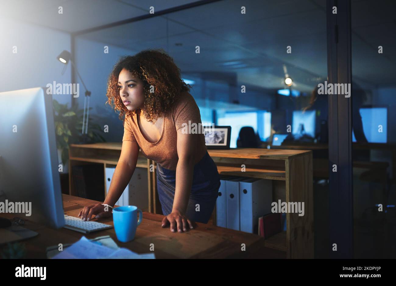 Eine junge Frau, die spät in einem leeren Büro arbeitet. Stockfoto