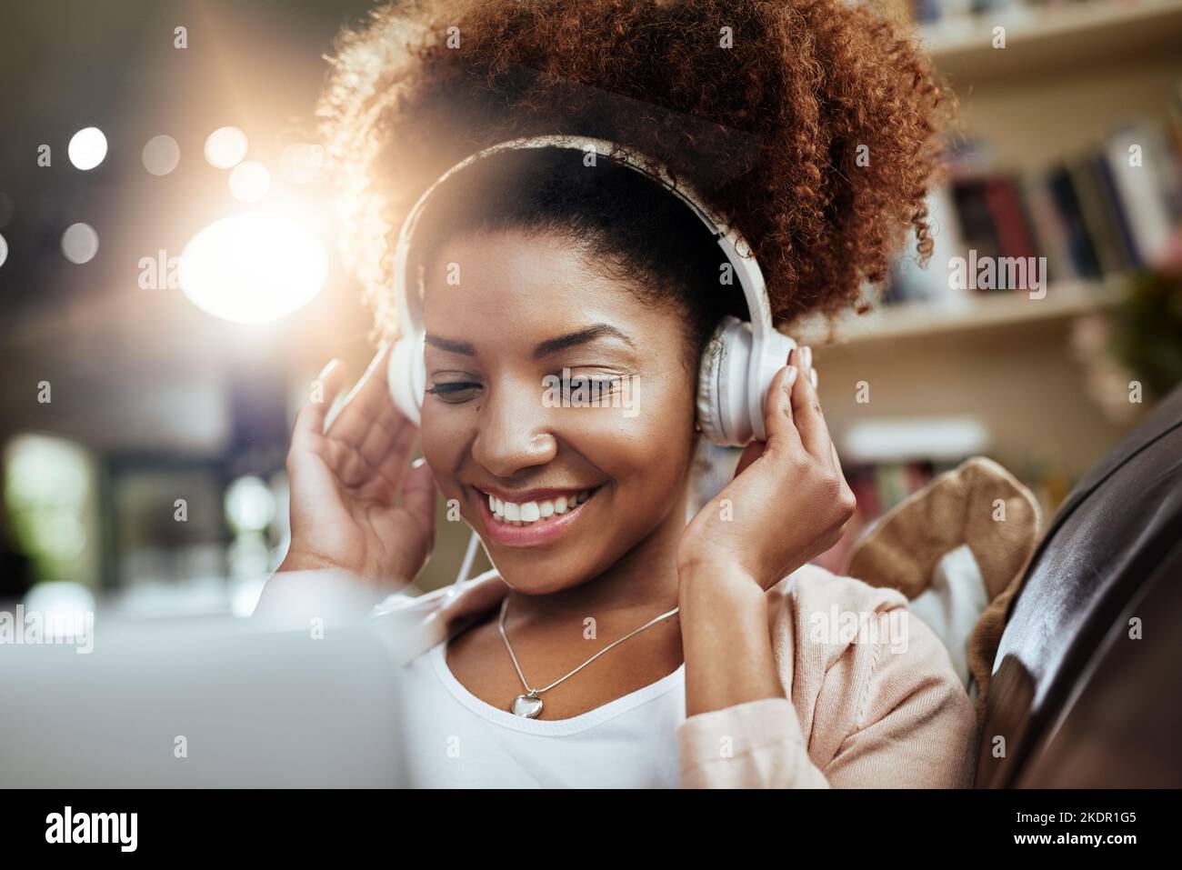 Das ganze Wochenende lang Musikvideos. Eine junge Frau, die sich auf dem Sofa entspannt und Musik auf ihrem Laptop hört. Stockfoto