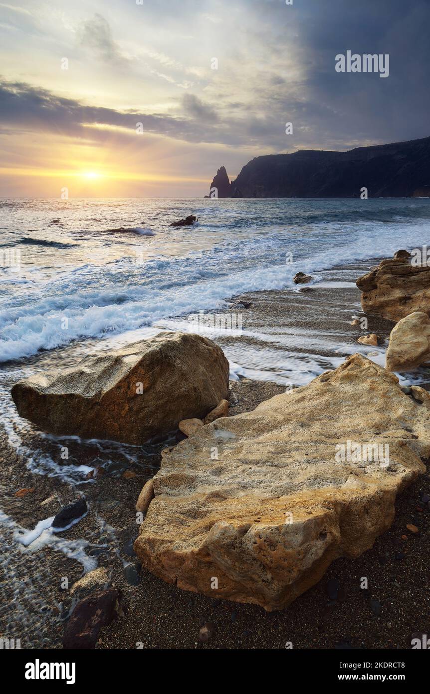 Abends Meerlandschaft mit der untergehenden Sonne am Strand und Felsen. Krim, Ukraine, Europa Stockfoto