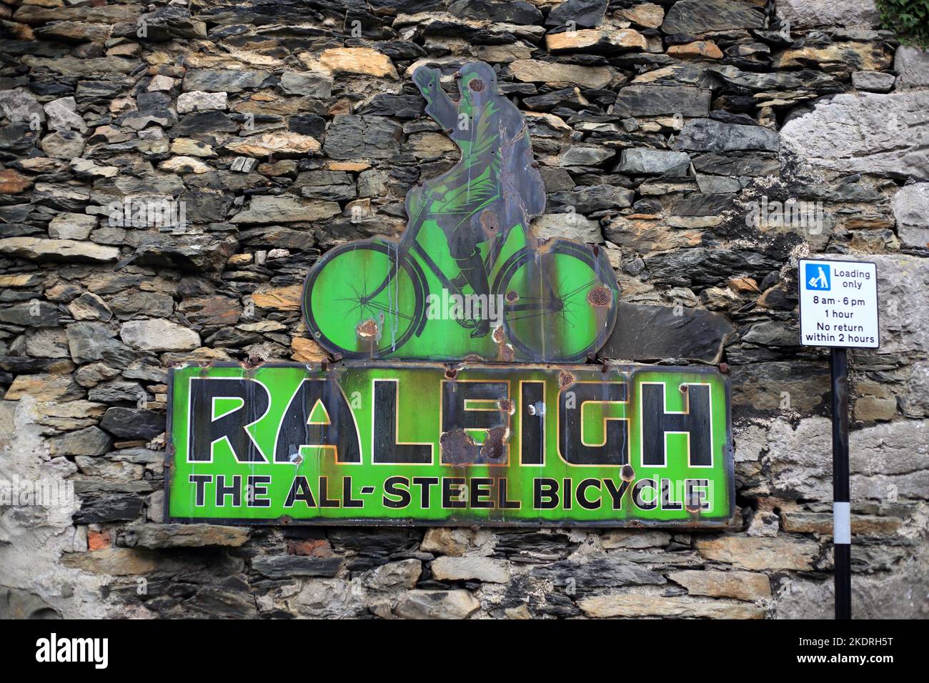 Altes emailliertes Werbeschild für Raleigh-Fahrräder an einer Wand in Cartmel Village, Cumbria, England, Großbritannien. Stockfoto