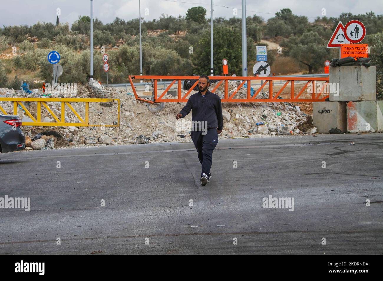 Qalqilya, Palästina. 8.. November 2022. Ein Palästinenser geht am Eingang des Dorfes Azzun vorbei, nachdem die israelische Armee es mit Erdhügeln und eisernen Toren blockiert hatte. Die israelische Armee schloss das Tor des Dorfes Azzun, östlich der Stadt Kalqilya im Westjordanland, nachdem palästinensische Jugendliche Steine auf die Fahrzeuge jüdischer Siedler geworfen hatten. Die israelische Armee teilte mit, dass ein israelischer Siedler aus der Siedlung Kedumim infolge seiner Wunden getötet wurde, die er erlitten hatte, nachdem er von einem Palästinenser erstochen wurde. Stockfoto