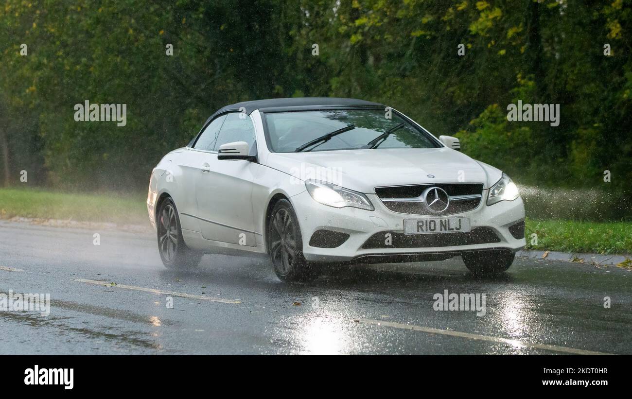 2014 weißer Mercedes Benz E fährt im Regen auf nasser Straße Stockfoto