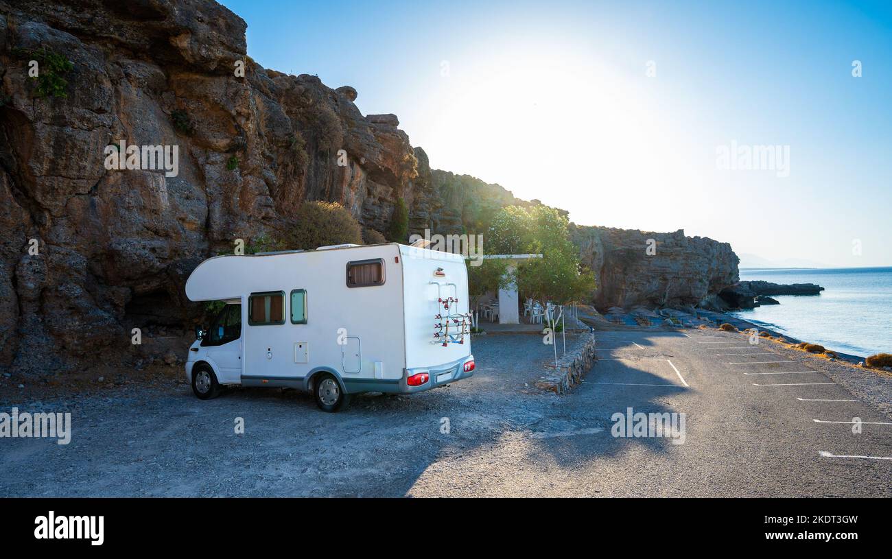 Wohnmobil-Wohnmobil am Strand unter einer Klippe, Kreta, Griechenland geparkt. Familienreisen mit Wohnmobil ist am Strand geparkt. Reisende mit Wohnmobil sind Camping Stockfoto