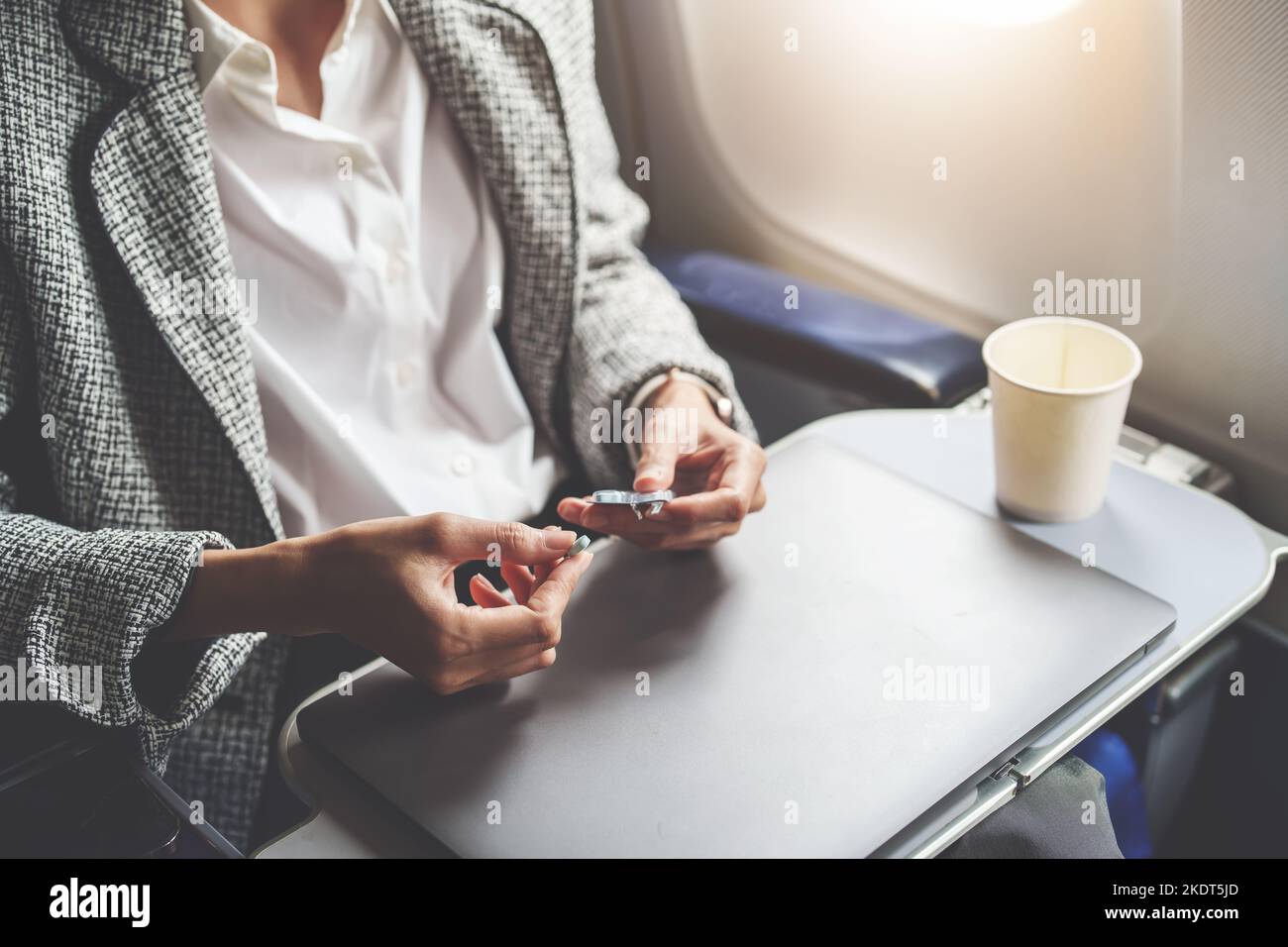 Eine erfolgreiche asiatische Geschäftsfrau oder Unternehmerin in einem formellen Anzug auf einem Flugzeug in der Business Class, die während des Fluges Flugpillen nimmt Stockfoto