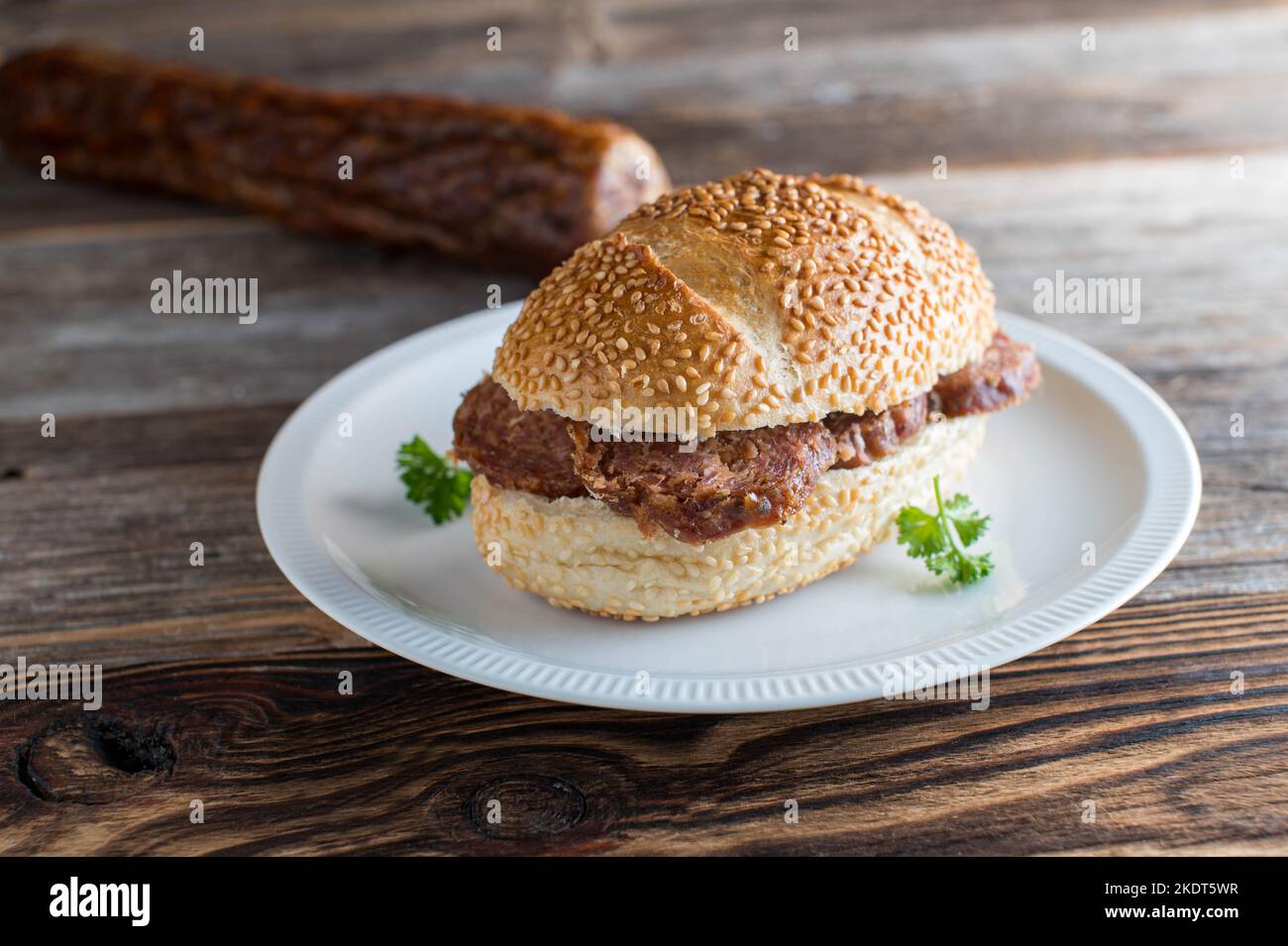 Sesambrötchen mit hausgemachter Salami. Traditionelles deutsches Sandwich Stockfoto