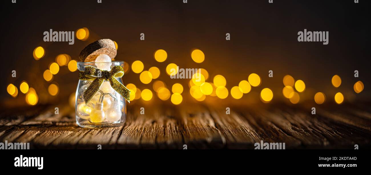 Kleines Glas mit Weihnachtsbeleuchtung auf Holzplanken Stockfoto