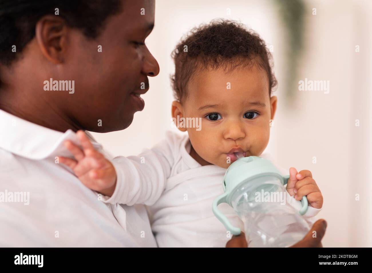 Schwarzer Junge Trinkt Wasser Aus Der Flasche, Während Er Zeit Mit Dem Vater Verbringt Stockfoto