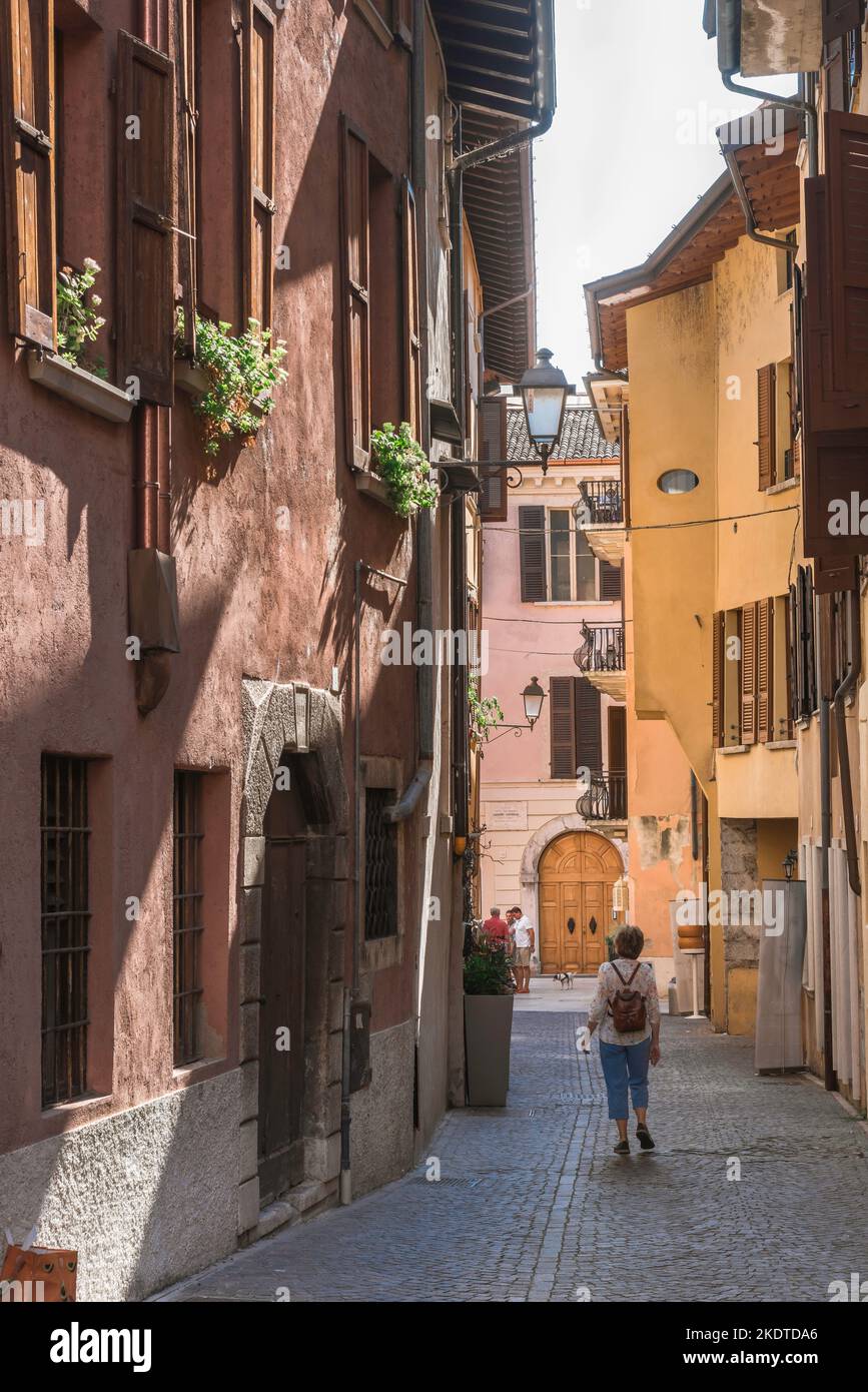 Reife Frauen reisen, Rückansicht im Sommer einer Frau mittleren Alters, die einen Rucksack trägt und alleine eine malerische Straße in einer italienischen Stadt, Italien, Europa, erkundet Stockfoto