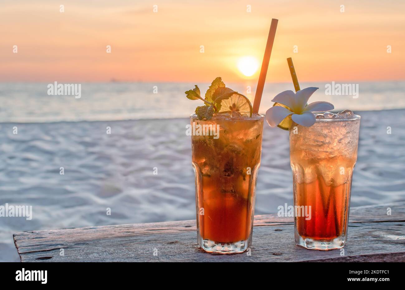 Getränke mit verschwommenem Strand und Sonnenuntergang im Hintergrund Stockfoto