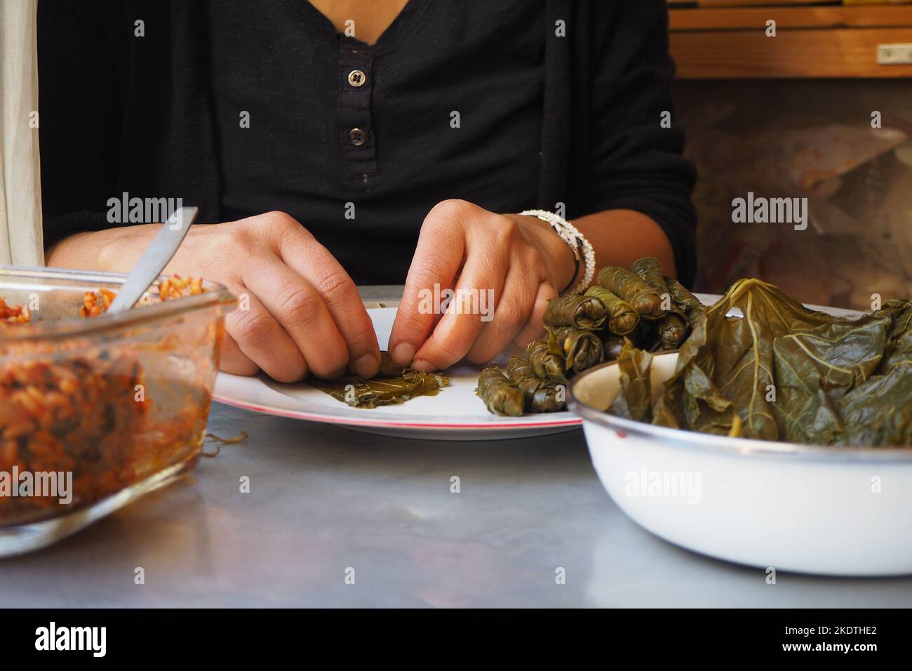 Traubenblätter gefüllt mit Reis und Kräutern.Frau Vorbereitung verpackte Blatt. Gefüllte Traubenblätter bereit zum Kochen. Türkische traditionelle Küche, Yaprak Sarma. Stockfoto