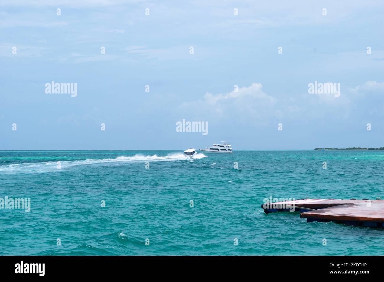 Ein Bild von einem Schnellboot, das sich auf ein Kreuzfahrtschiff im blauen Meer zubewegt Stockfoto