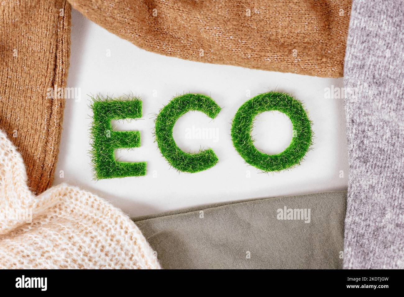 Konzept für umweltfreundlich produzierte Kleidung mit dem Text „ECO“ aus Gras, umgeben von Textilien Stockfoto