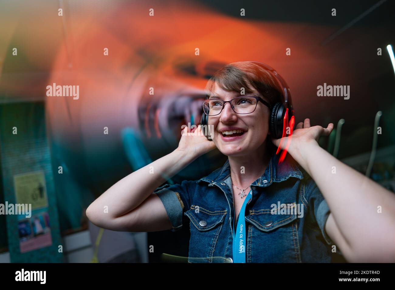 Eine Frau mit Kopfhörern in einer stillen Disco in einer Bibliothek Stockfoto