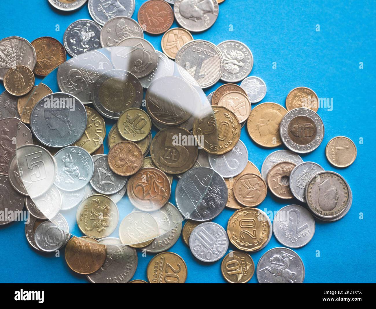 Münzsammlung mit einer Lupe erkunden. Anderes internationales Geld unter Lupe, selektiver Fokus Stockfoto