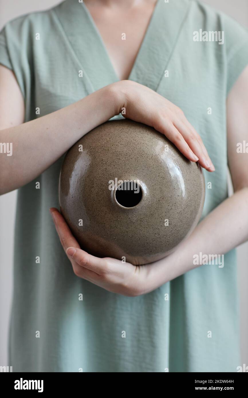 Vertikale Nahaufnahme von fair junge Frau mit kreisförmigen Keramikvase menschlichen Design zen Stockfoto