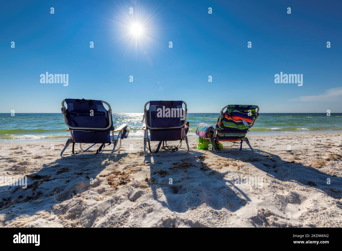 Sonniger tropischer Strand und Liegestühle in weißem Sand und Sonnenlicht Stockfoto Sonniger tropischer Strand und Liegestühle in weißem Sand und Sonnenlicht Stockfoto