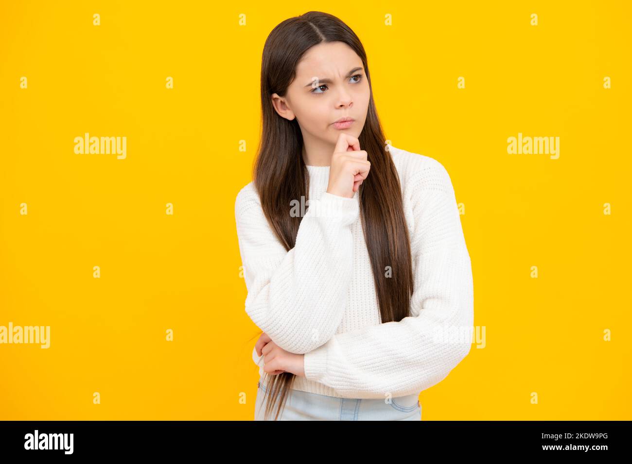 Denkende Teenager Mädchen, nachdenkliche Emotion. Smart nerdy Schule Mädchen berühren Wange und Denken vor gelbem Hintergrund. Kind denken und Idee Stockfoto