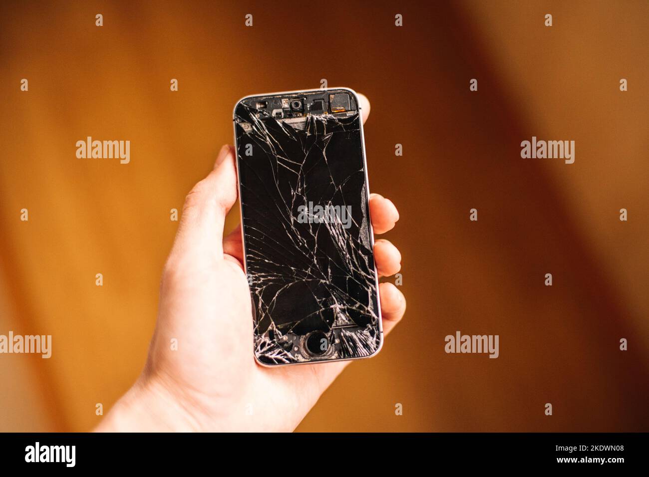 Person, die in der Hand hält, kaputtes Smartphone mit gesprungenem Bildschirm Stockfoto