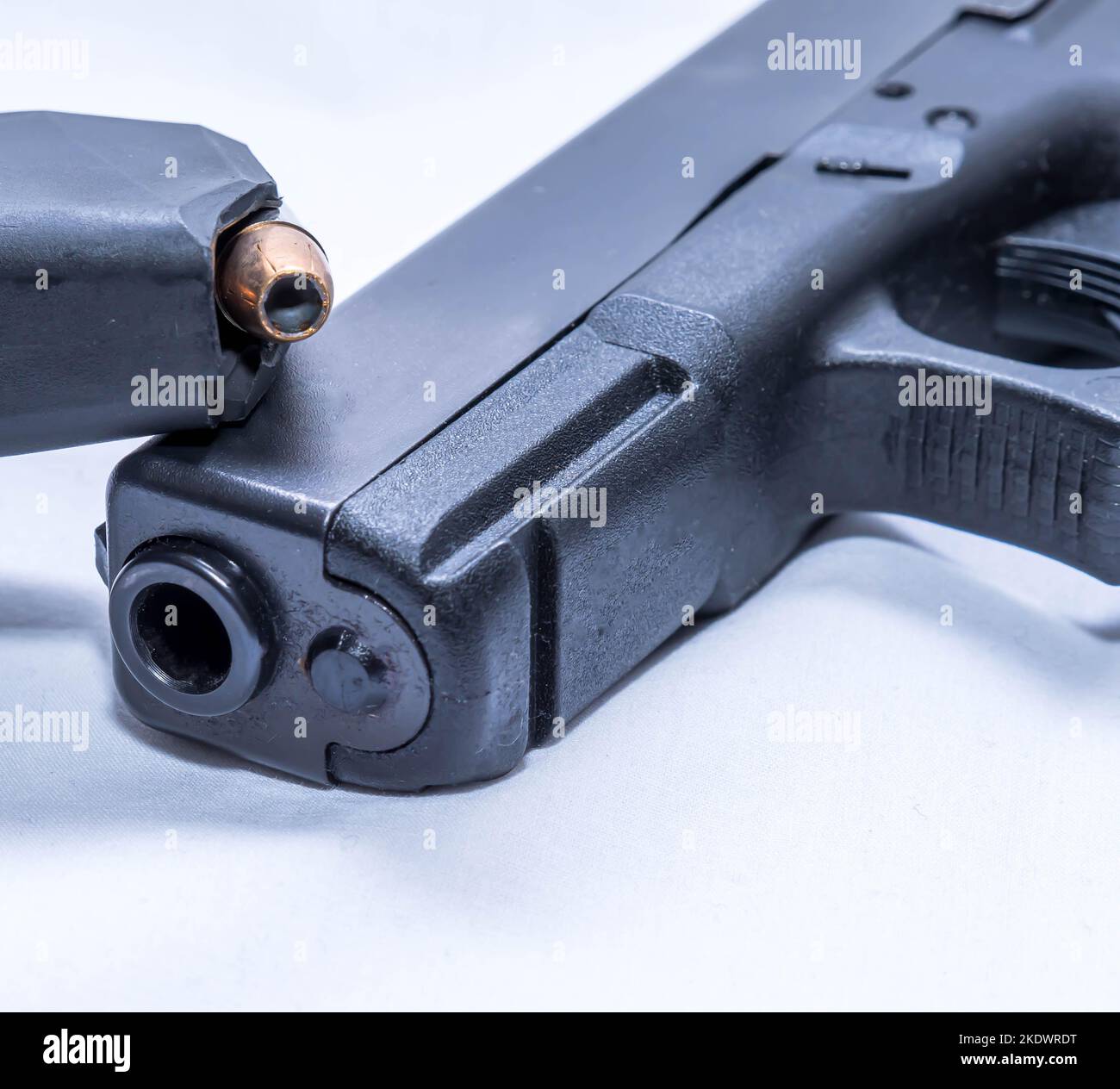 Eine Pistolenzeitschrift aus dem Jahr 9mm, die mit hohlen Punktekugeln auf einer schwarzen Pistole aus dem Jahr 9mm auf weißem Hintergrund bestückt ist Stockfoto