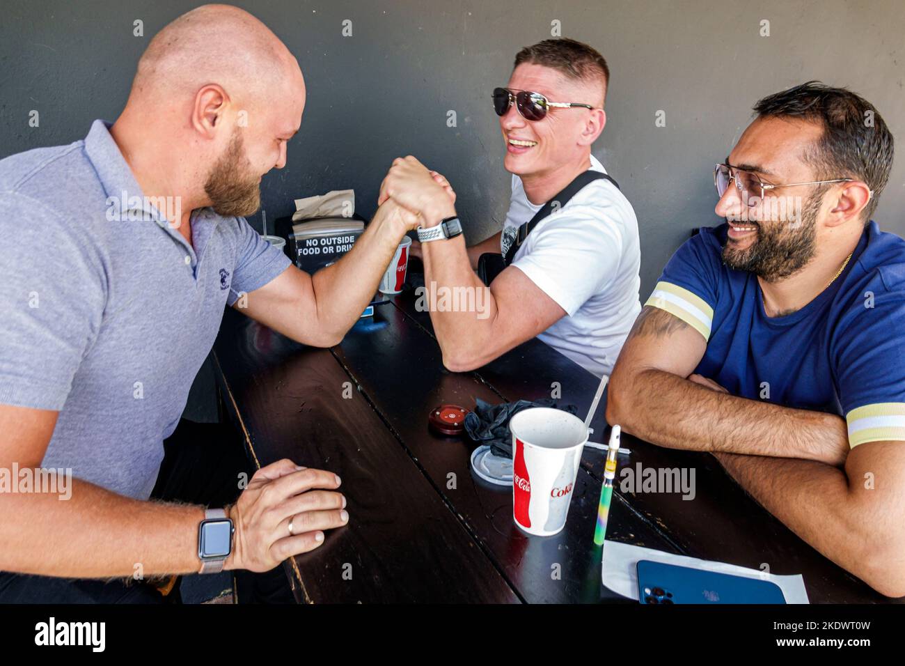 Miami Beach Florida, North Beach Hispanic Mann Männer männlich Erwachsene Erwachsene, Freunde Arm Wrestling Stärke Test Spaß lächelnd, Stockfoto