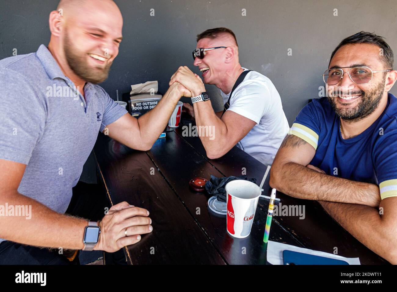 Miami Beach Florida, North Beach Hispanic Mann Männer männlich Erwachsene Erwachsene, Freunde Arm Wrestling Stärke Test Spaß lächelnd, Stockfoto