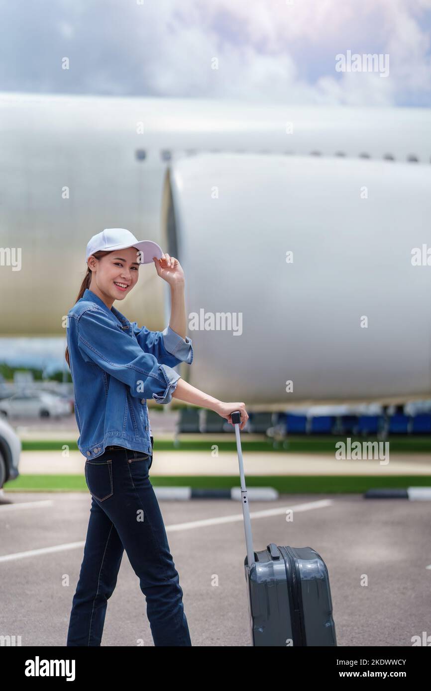 Porträt einer asiatischen Frau mit einem Koffer für eine Reise nach dem Aussteigen aus einem Economy-Class-Flugzeug, Konzepturlaub, Tourismus Stockfoto