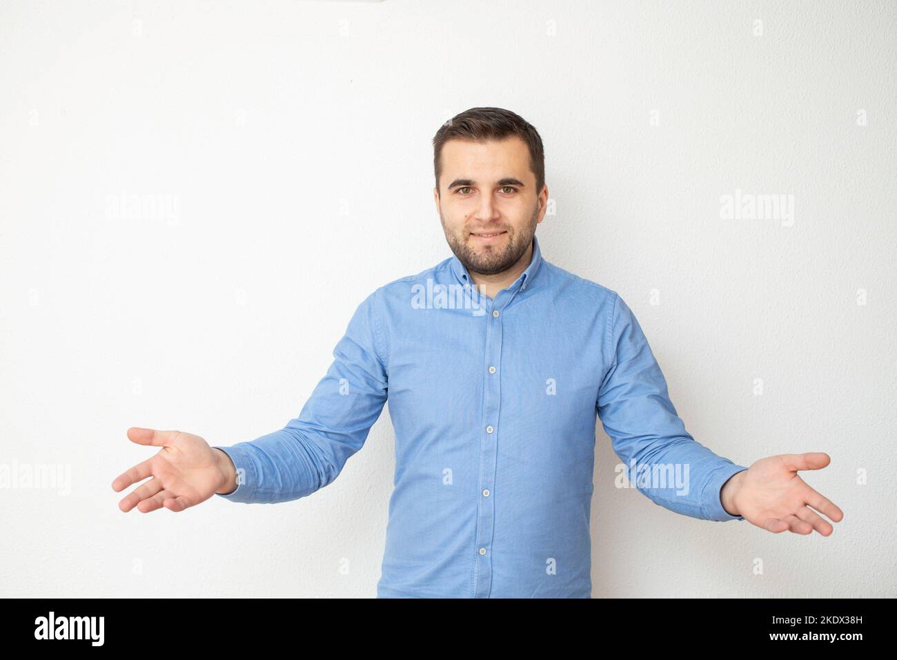 Kaukasisches männliches Model lächelt mit offenen Armen und ist in blauem Denim-Hemd gekleidet Stockfoto