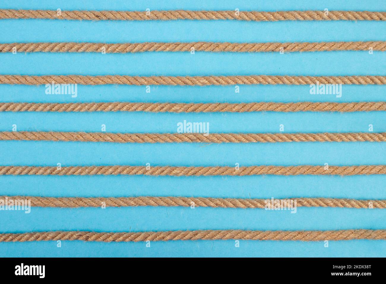 Juteseil waagerechte, in verschiedene Richtungen verdrehte Strichen, auf blauem Hintergrund, Nahaufnahme Stockfoto