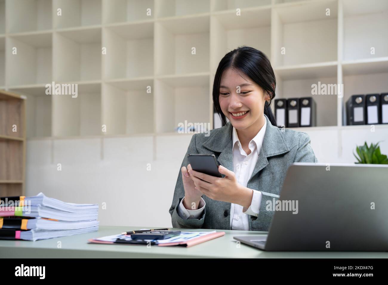 Schöne junge Geschäftsfrau mit Telefon im Büro Stockfoto