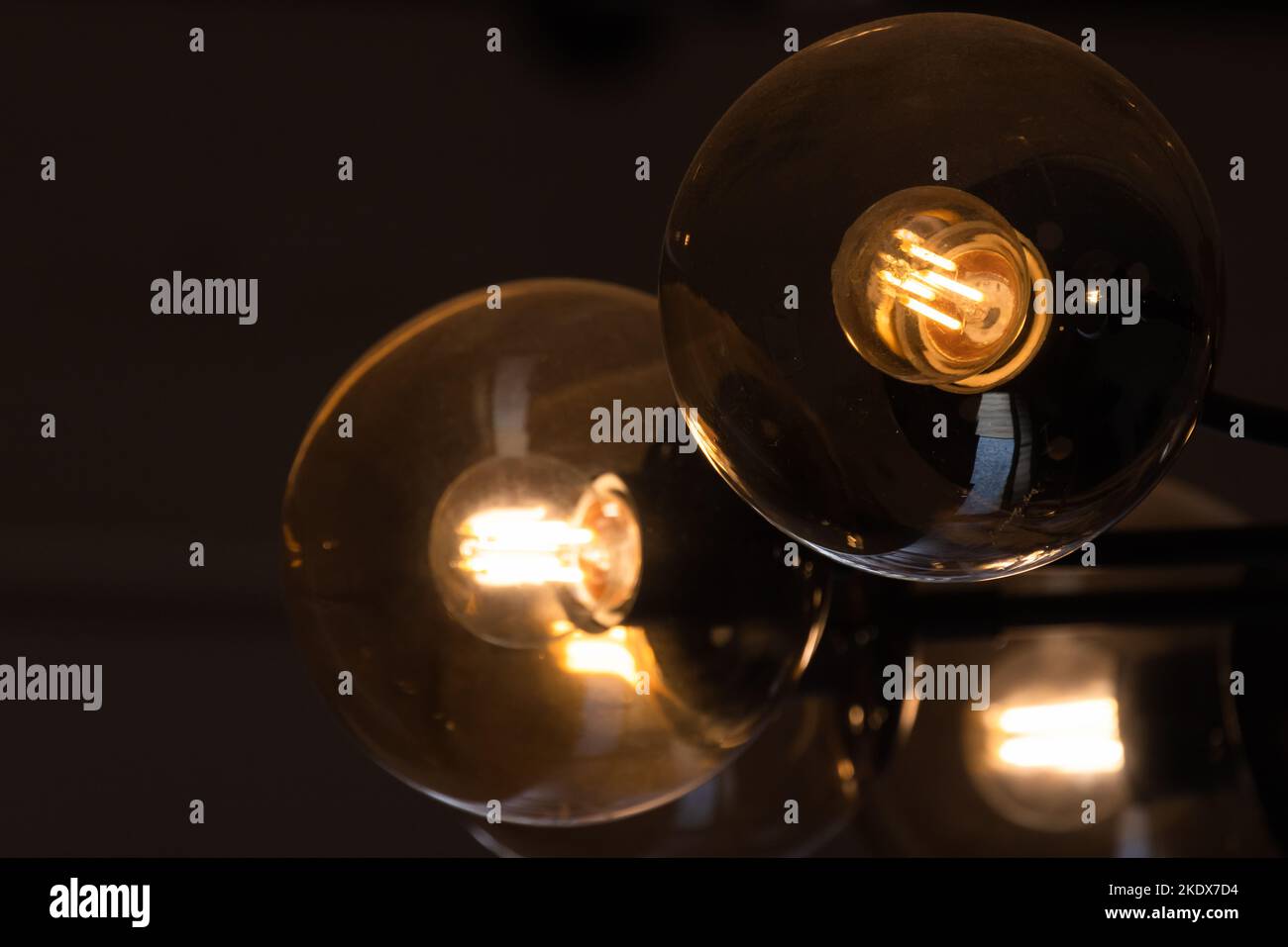 Wolfram-Lampen leuchten in runden Lampenschirmen aus Glas, Nahaufnahme mit selektivem Weichfokus Stockfoto