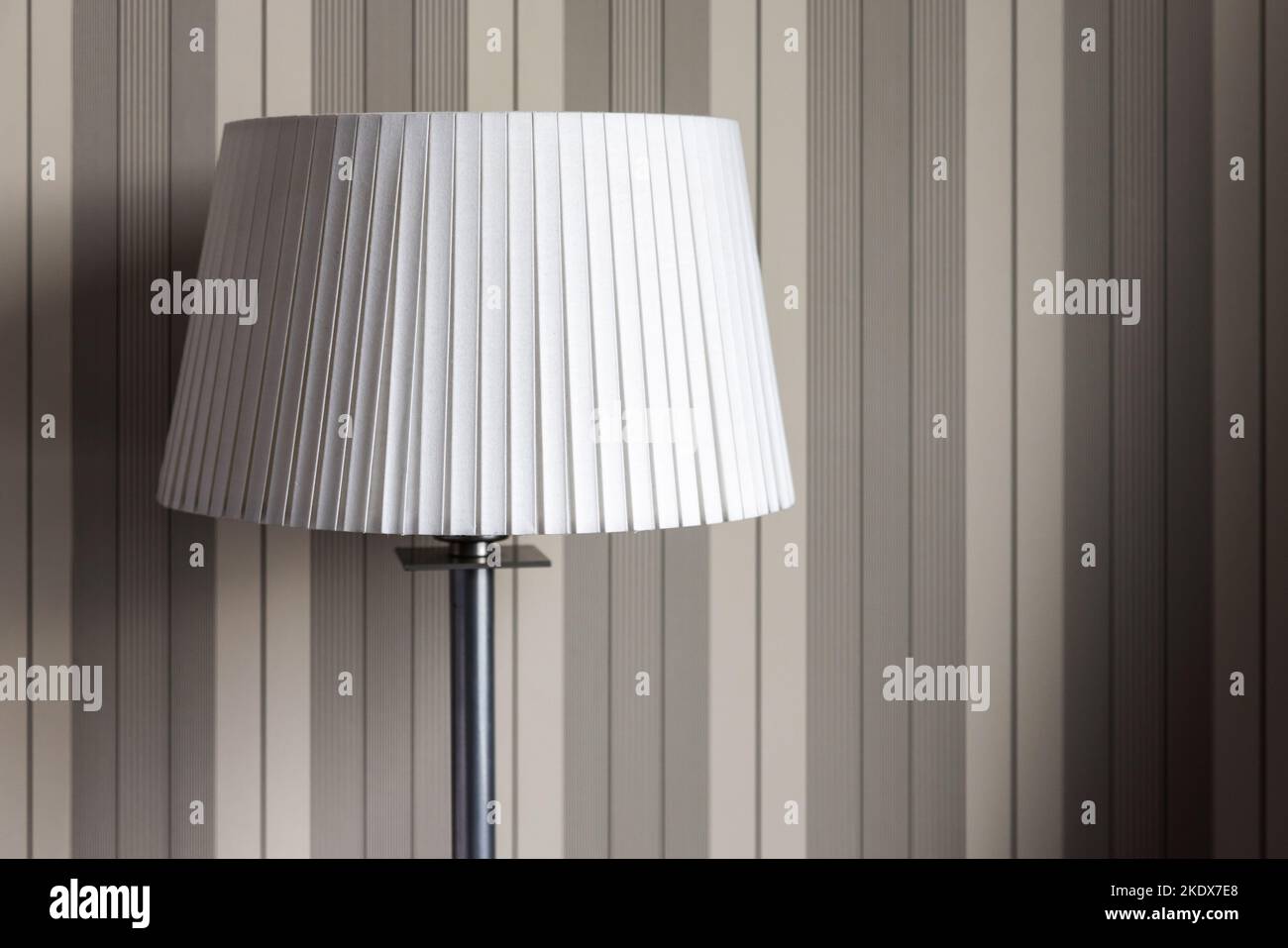 Stehleuchte mit weißem runden Lampenschirm steht neben der Wand, moderner Innenhintergrund Stockfoto