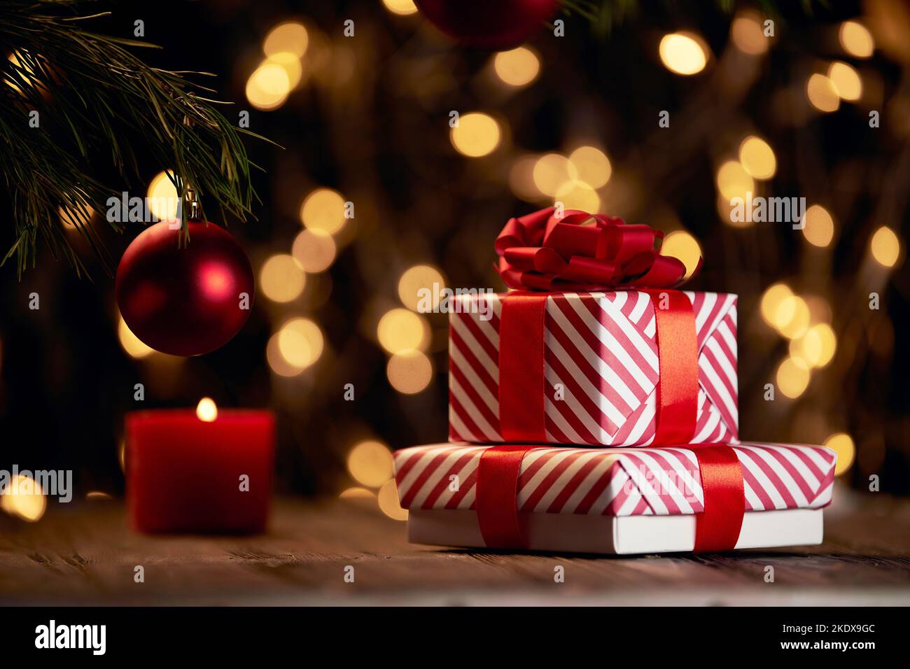 Geschenkboxen und eine rote Kerze auf weihnachtlichem Hintergrund. Stockfoto