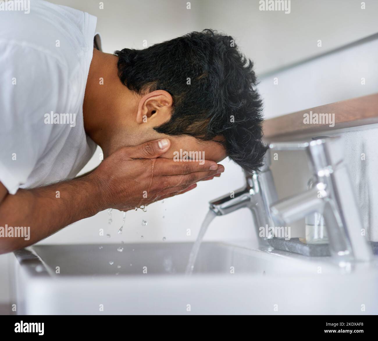 Schutz vor schlechter Haut. Ein junger Mann wäscht sich am Waschbecken im Bad das Gesicht. Stockfoto