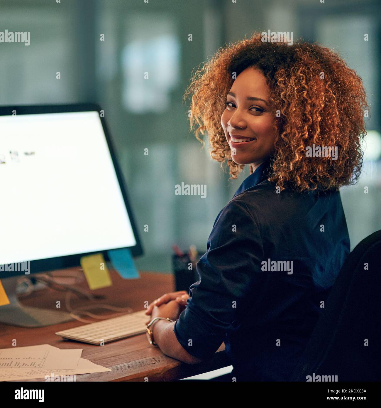 Positiv bleiben, produktiv bleiben. Porträt einer glücklichen jungen Geschäftsfrau, die einen Computer während eines späten Abends bei der Arbeit benutzt. Stockfoto