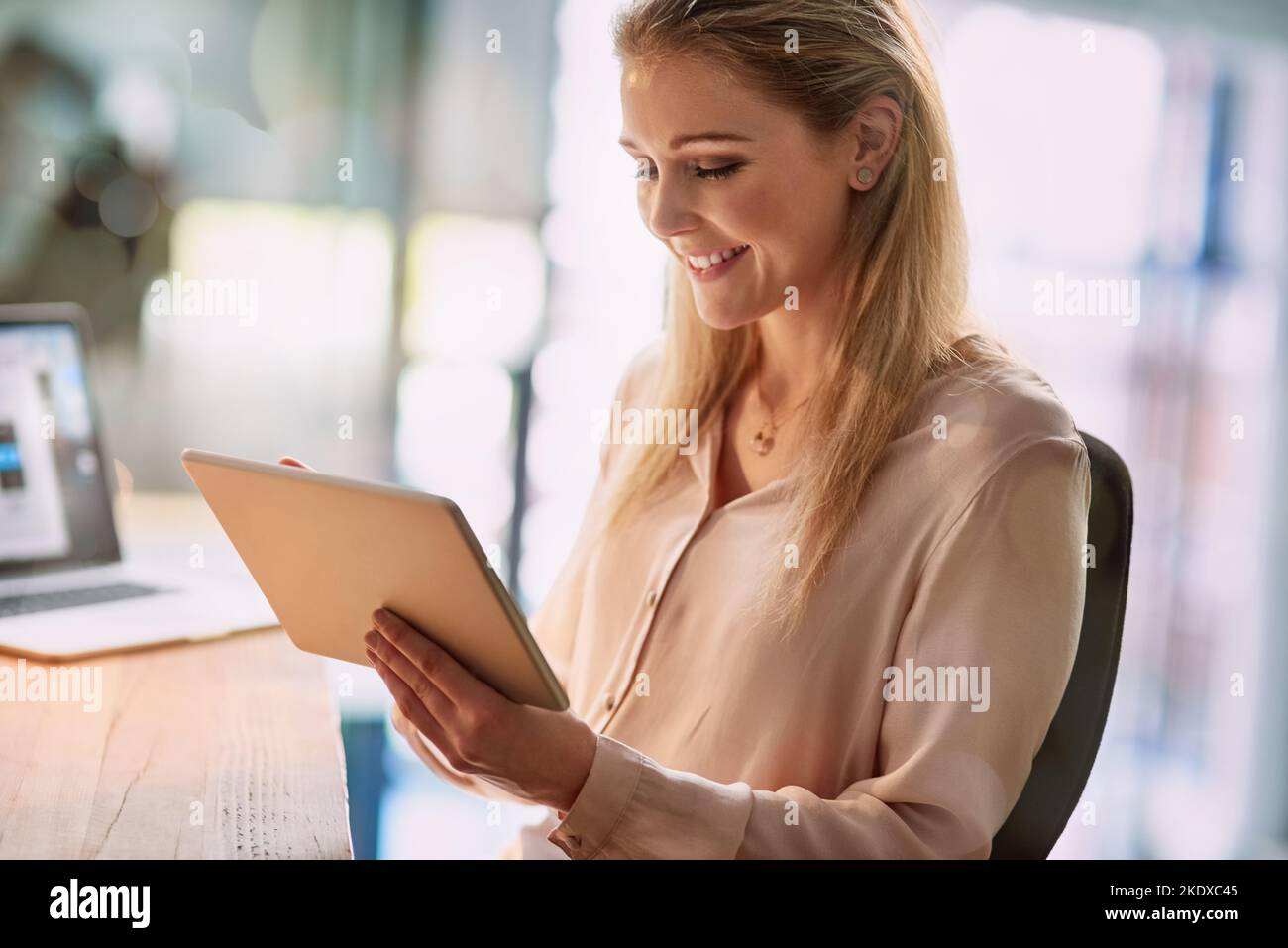 Die Technologie hält sie im Geschäft in Verbindung. Eine lächelnde junge Geschäftsfrau, die in einem Büro an einem digitalen Tablet arbeitet. Stockfoto